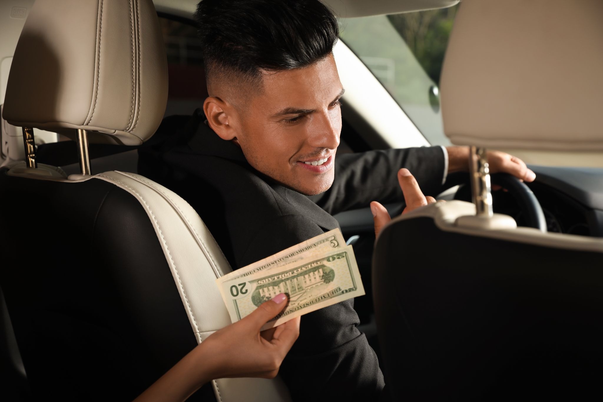 Lyft driver receiving cash payment from a passenger inside a car