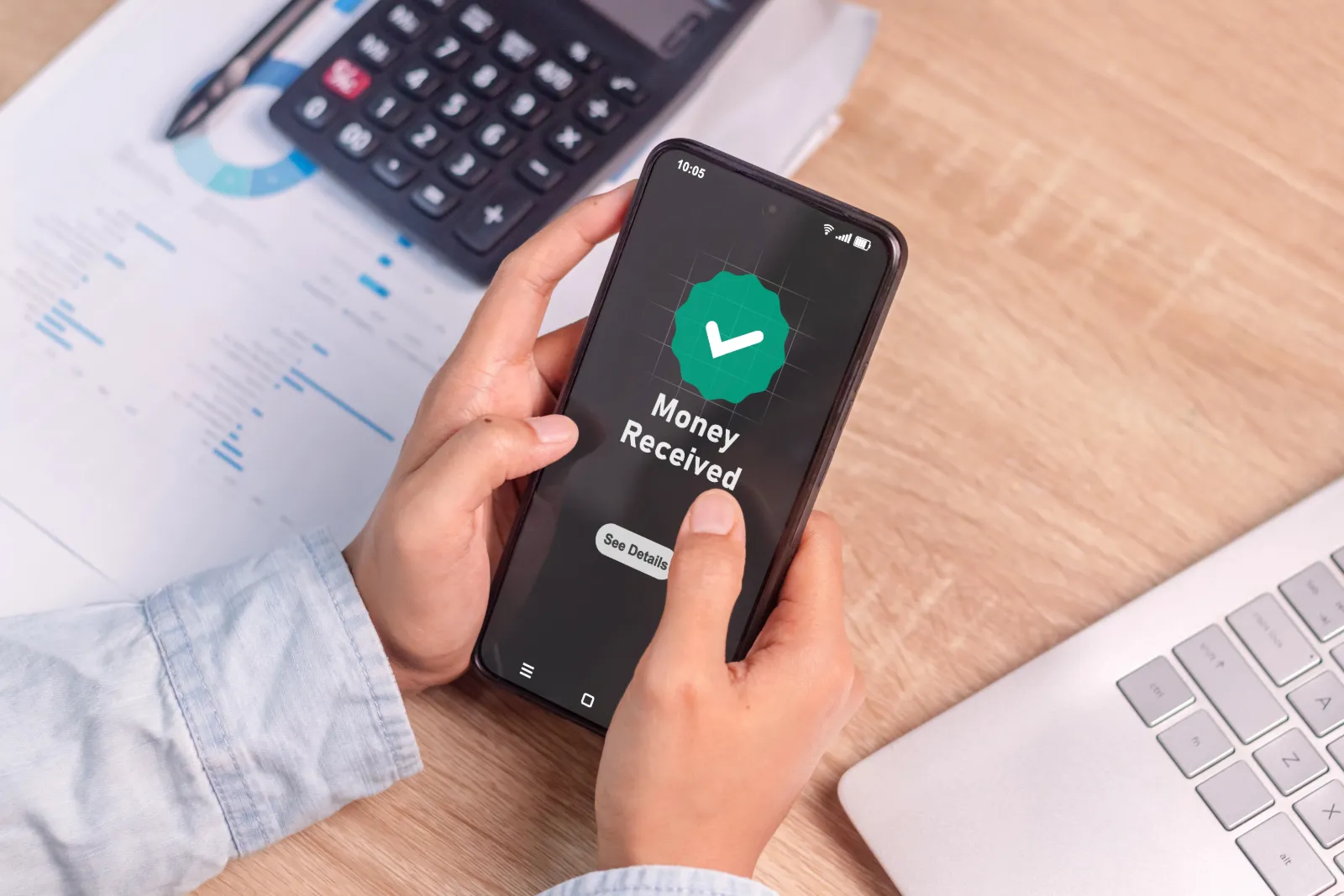 A person holding a phone showing a money received on phone screen.