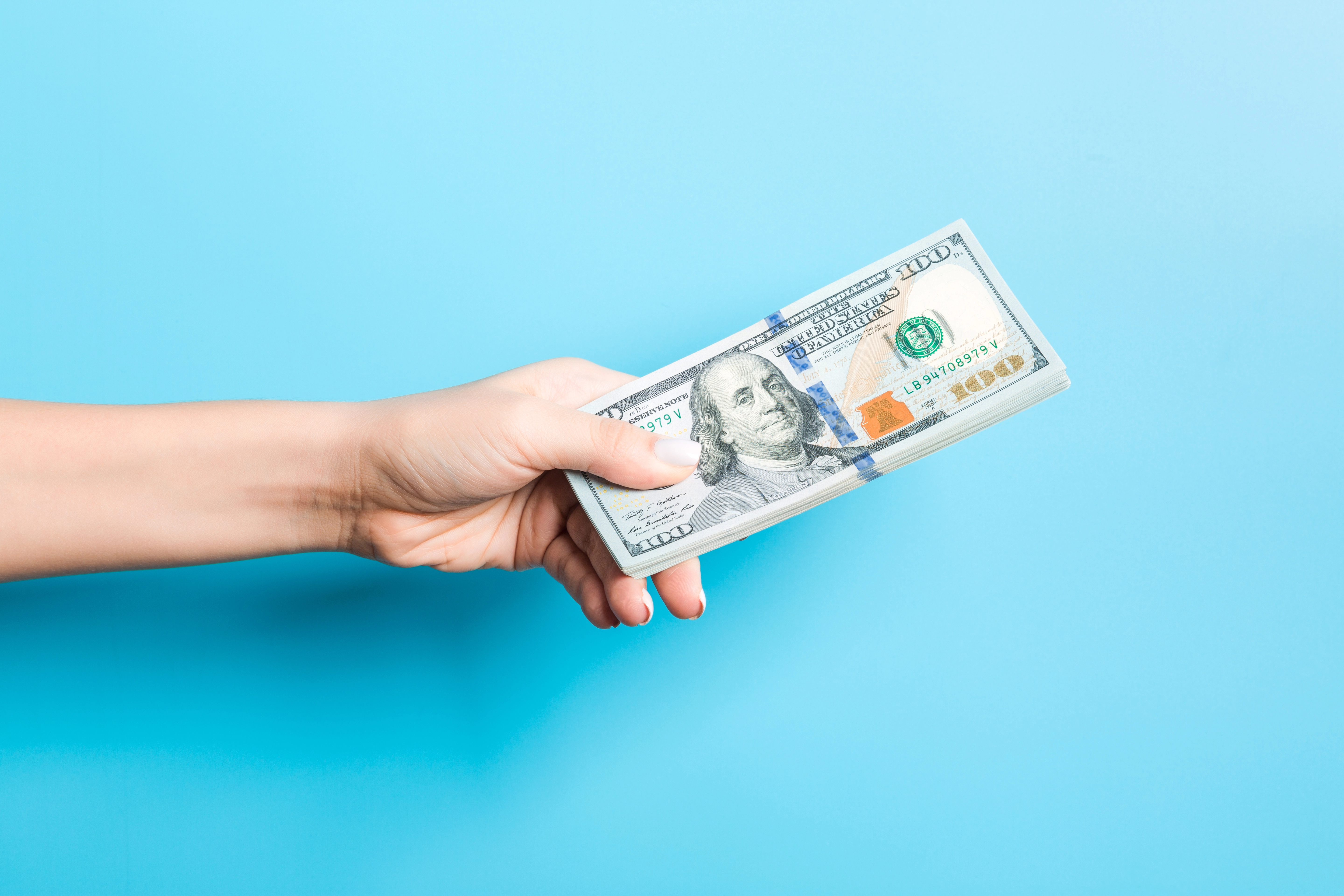 A hand holding 100 dollar bills.