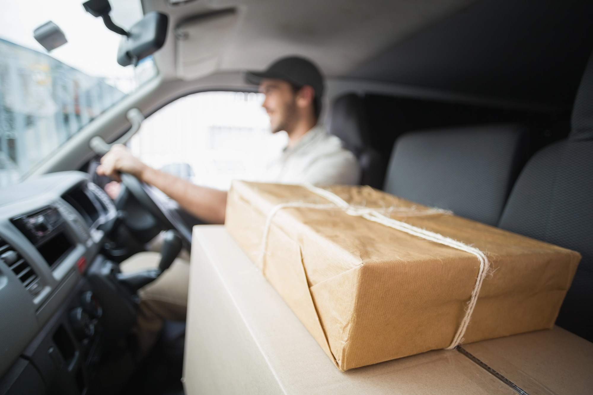 A happy independent courier driver delivering packages that are placed on the front seat