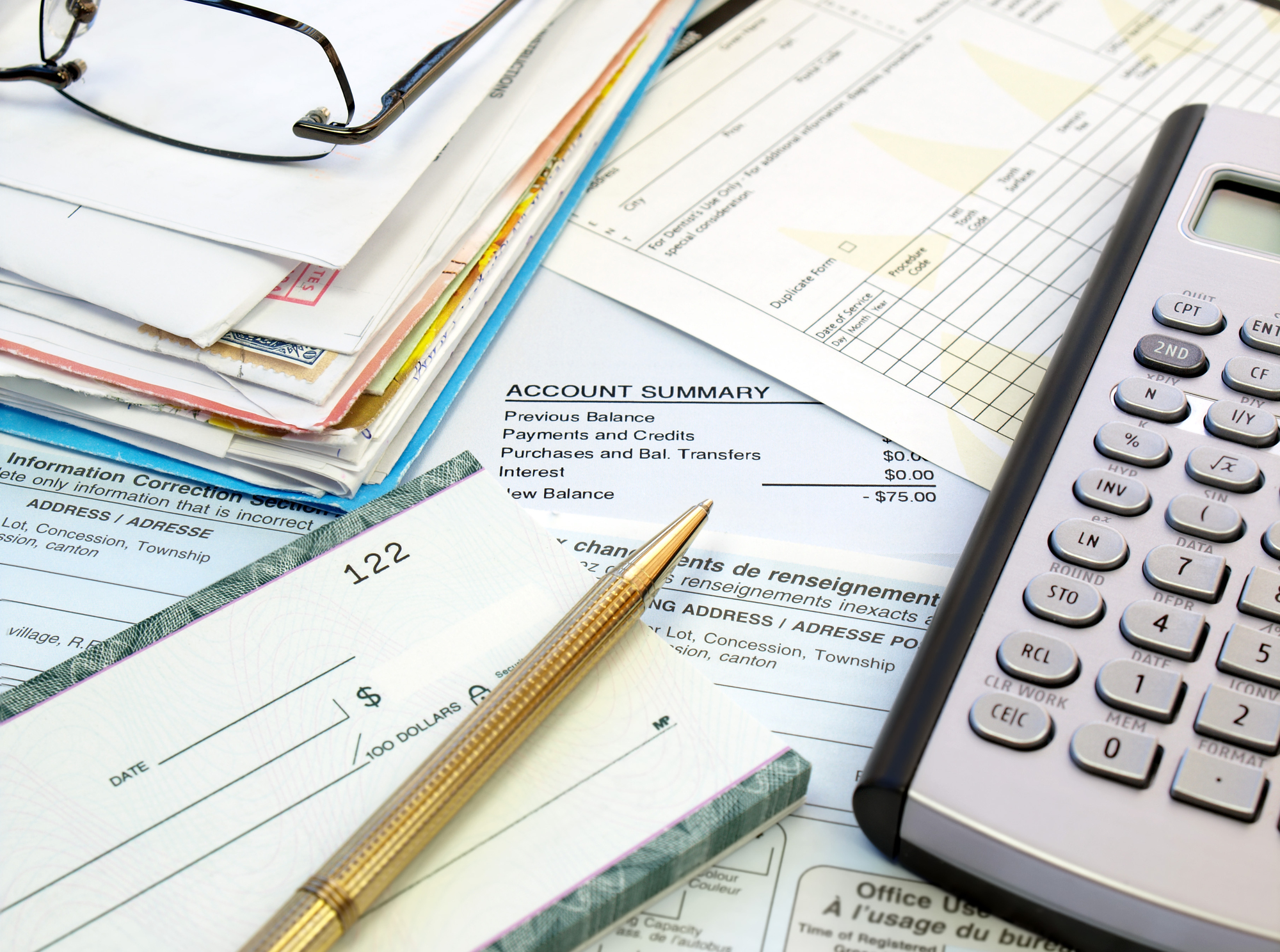 a calculator, check, and bills on top of a table