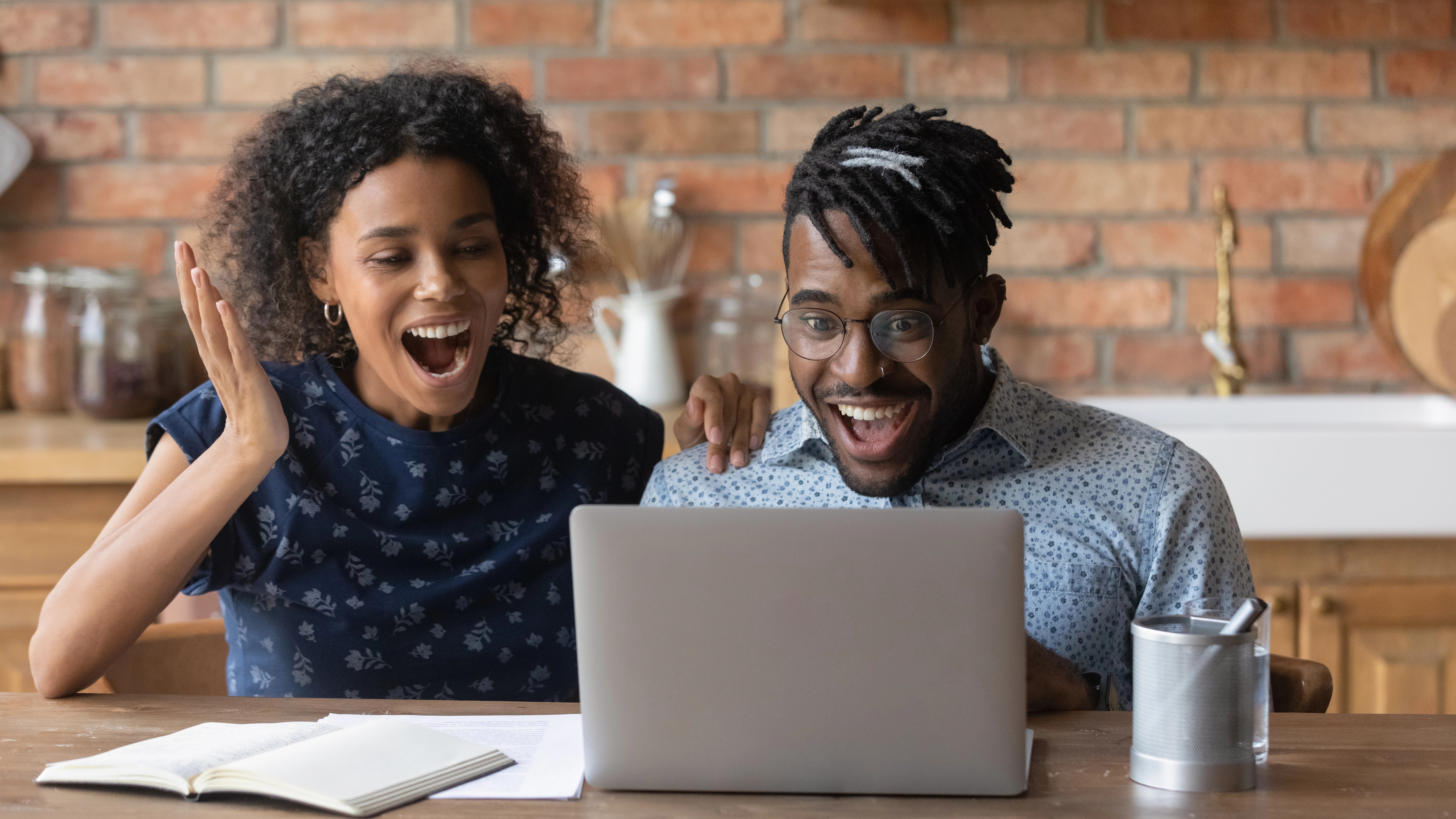 Two persons looking at the laptop screen with big smiles.