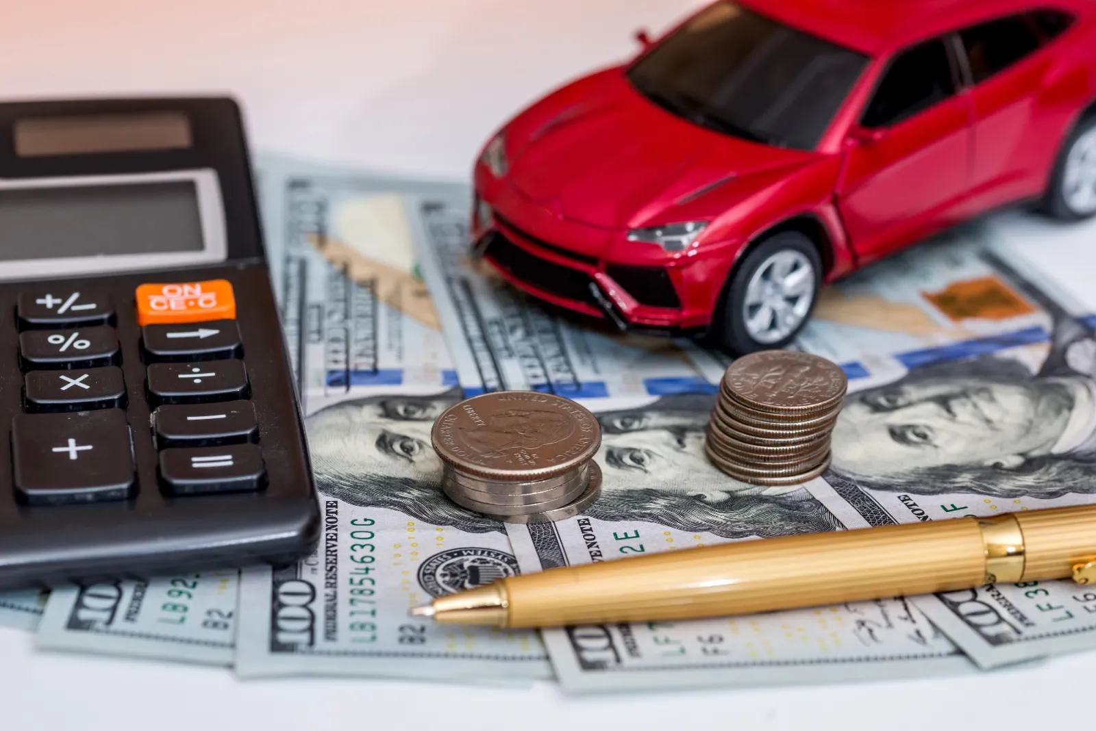 A toy car, cash, a calculator and a pen on a table