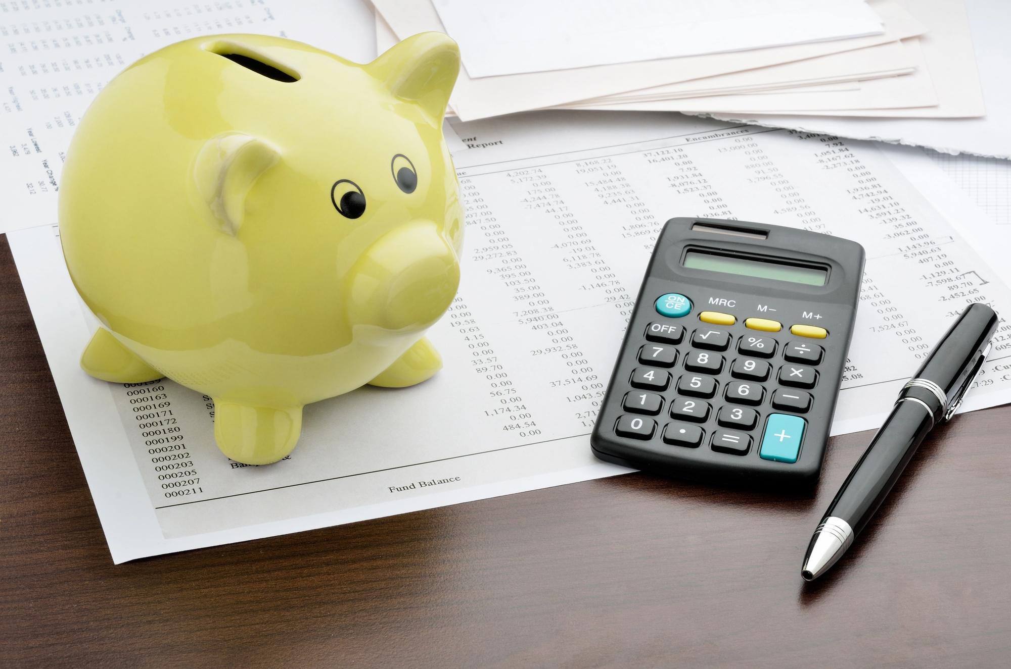 piggy bank, calculator, and pen on top of bank account documents