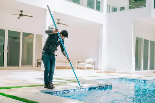 a freelance pool cleaner removing debris from a swimming pool