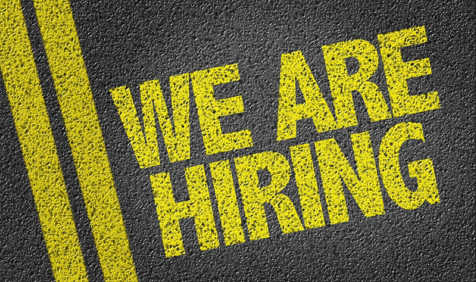 Yellow text on asphalt reading We Are Hiring..jpg