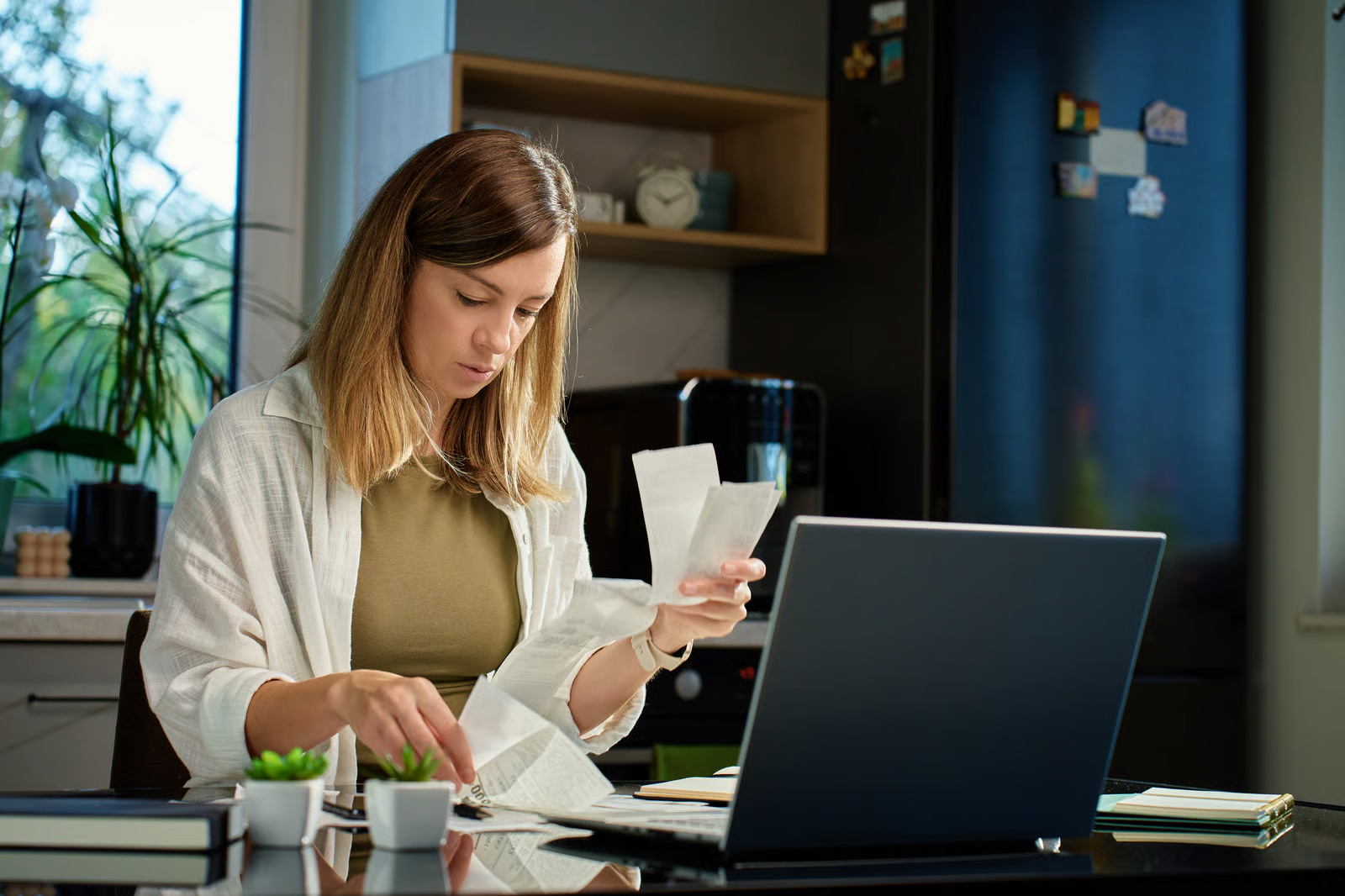  Gig worker organizing and reviewing bills one by one at a desk with papers spread out