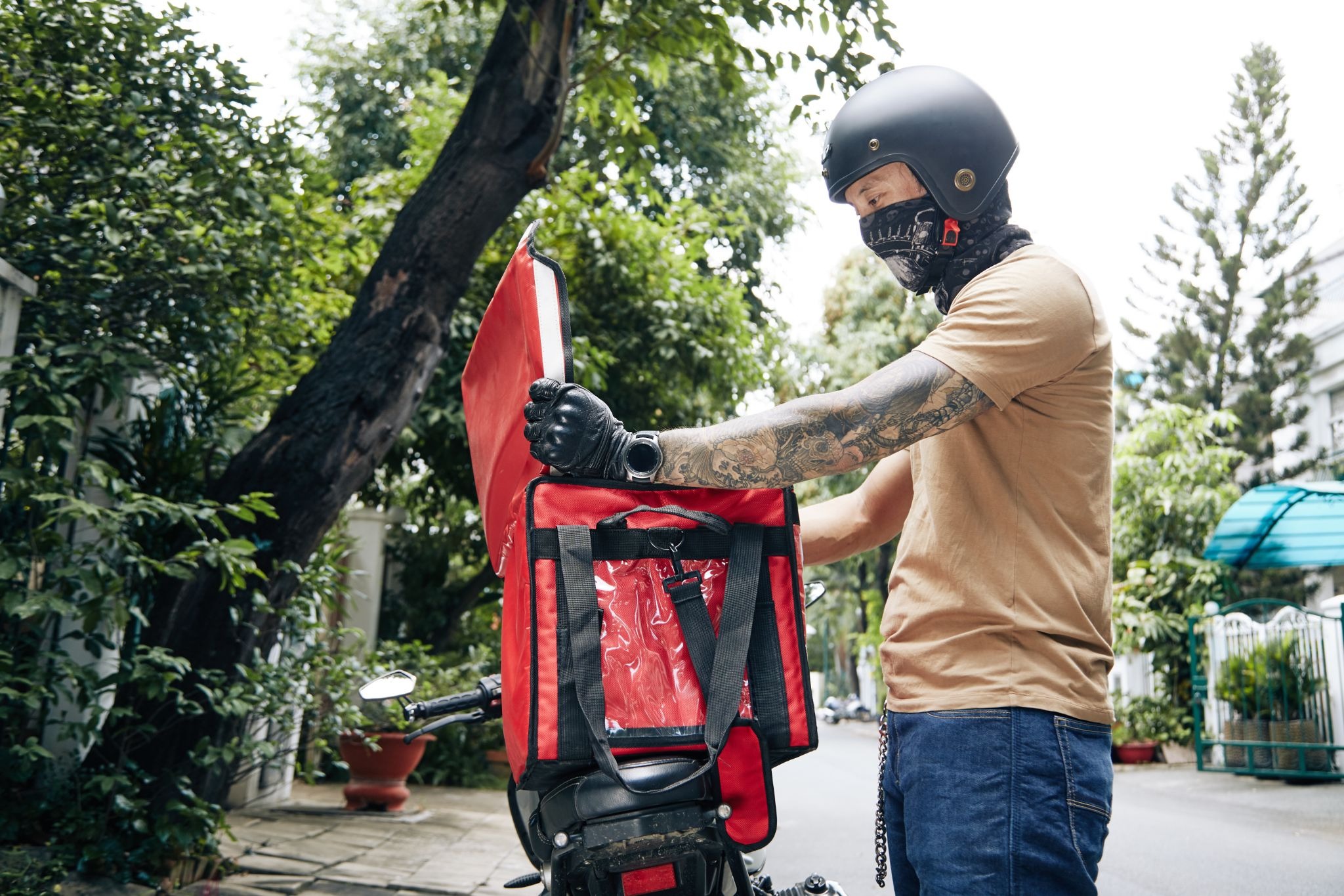 Delivery rider opening a thermal bag on a motorcycle to check an order