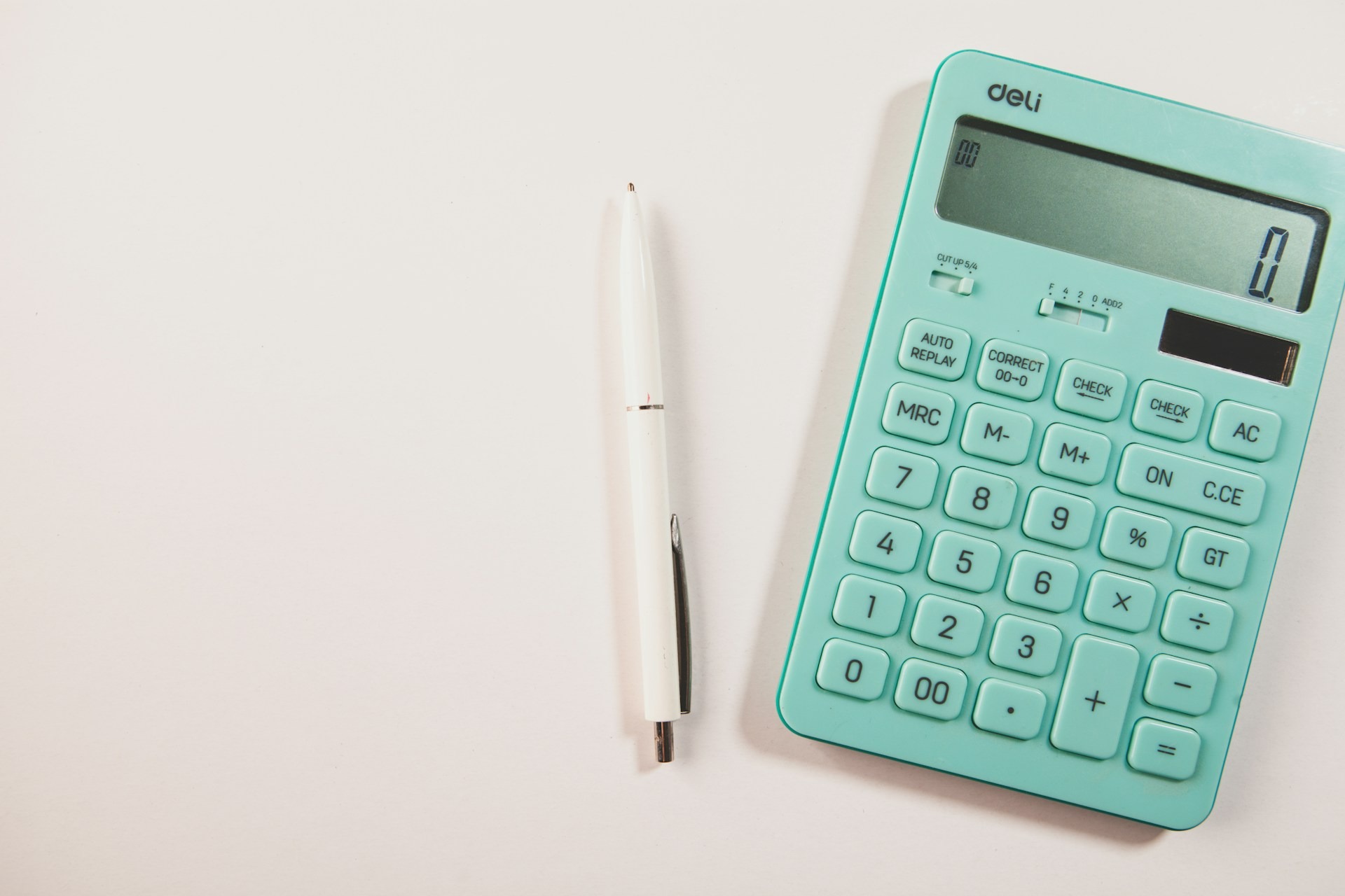 Calculator and pen on a white desk with copy space.