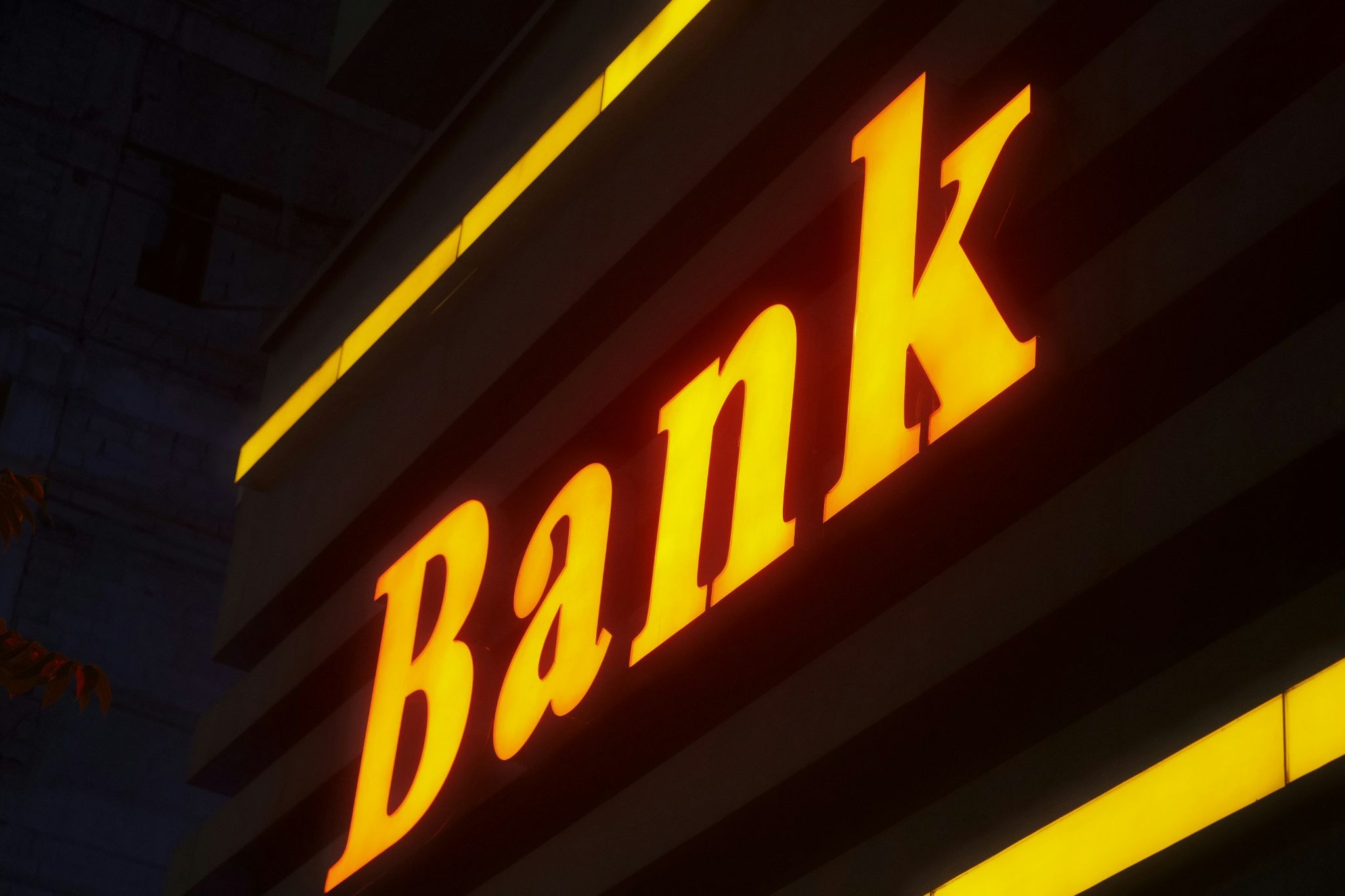Illuminated bank sign on a building exterior at night.