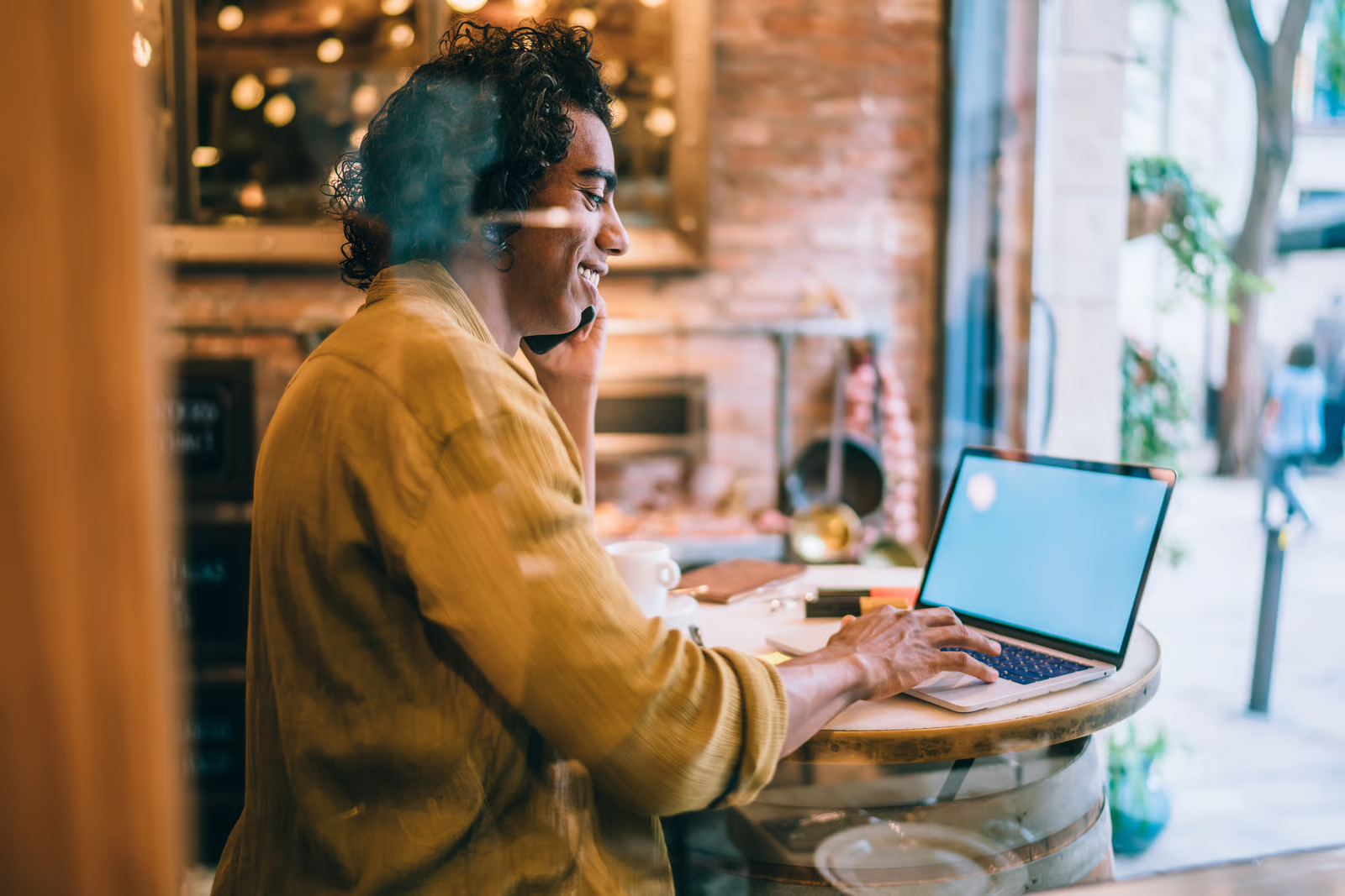 an excited freelancer working at a cafe while on the phone with a client