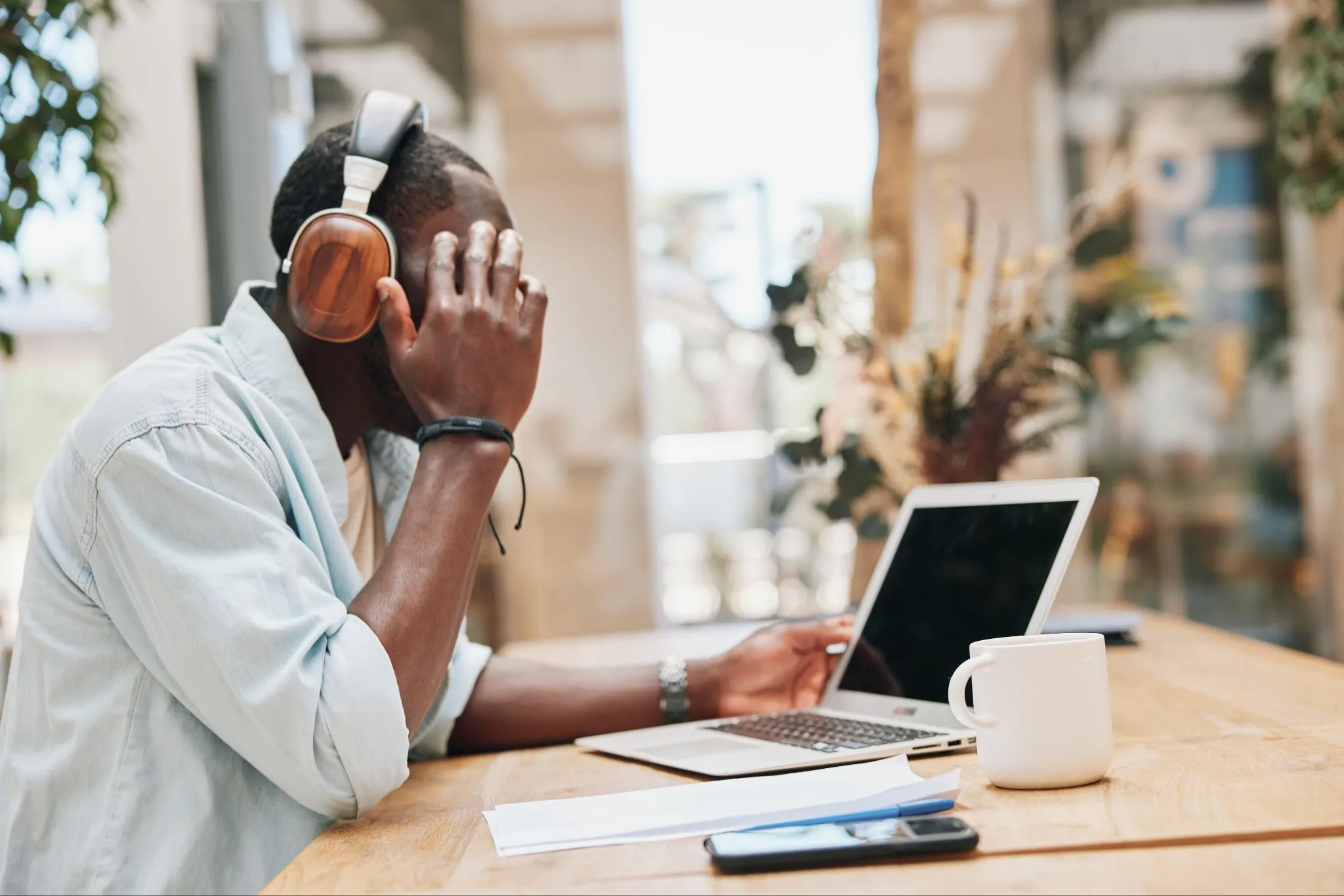 Freelance writer working on a laptop while wearing headphones in a cafe