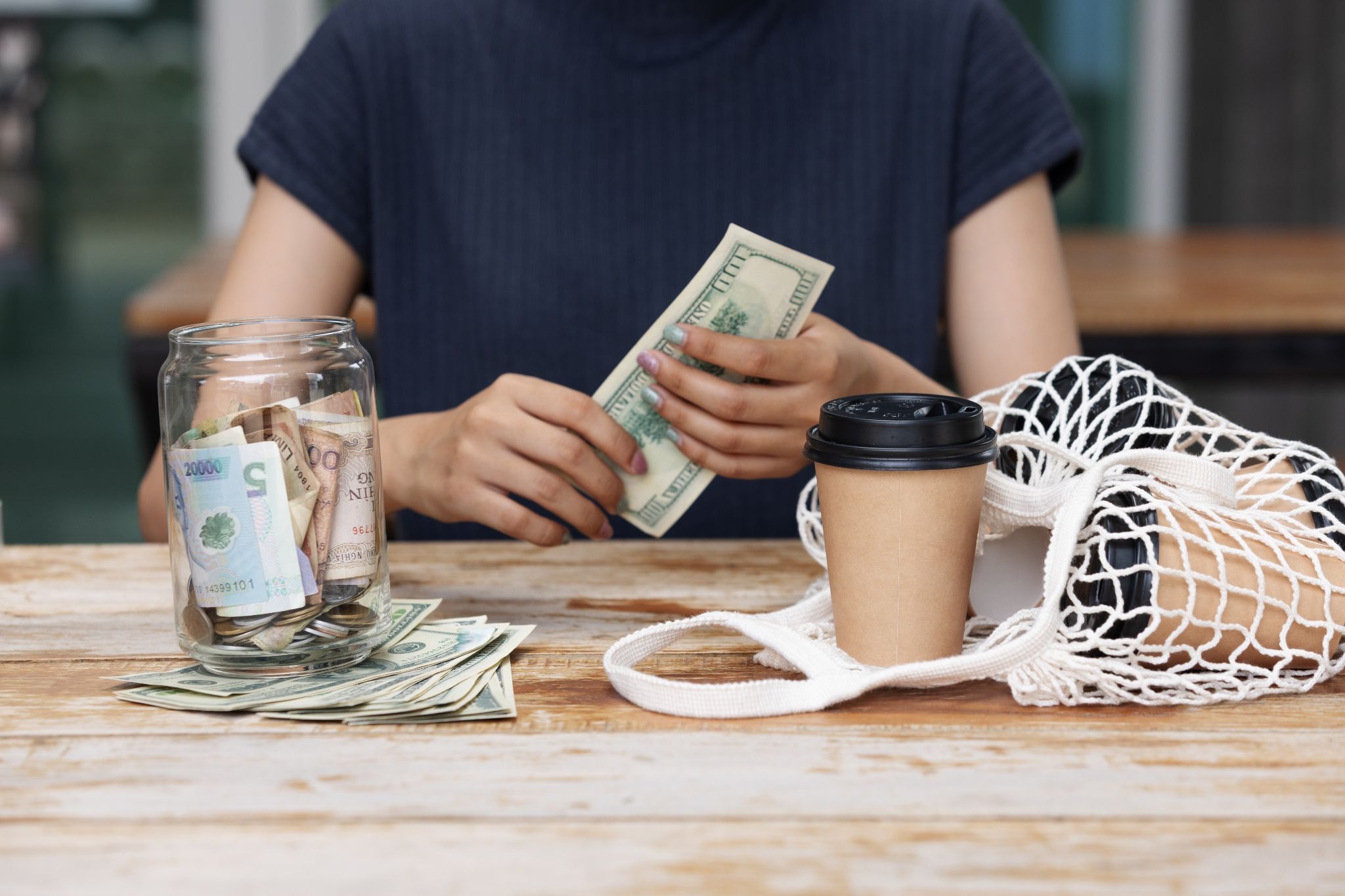 Instacart shopper counting earnings beside groceries, coffee, and a savings jar