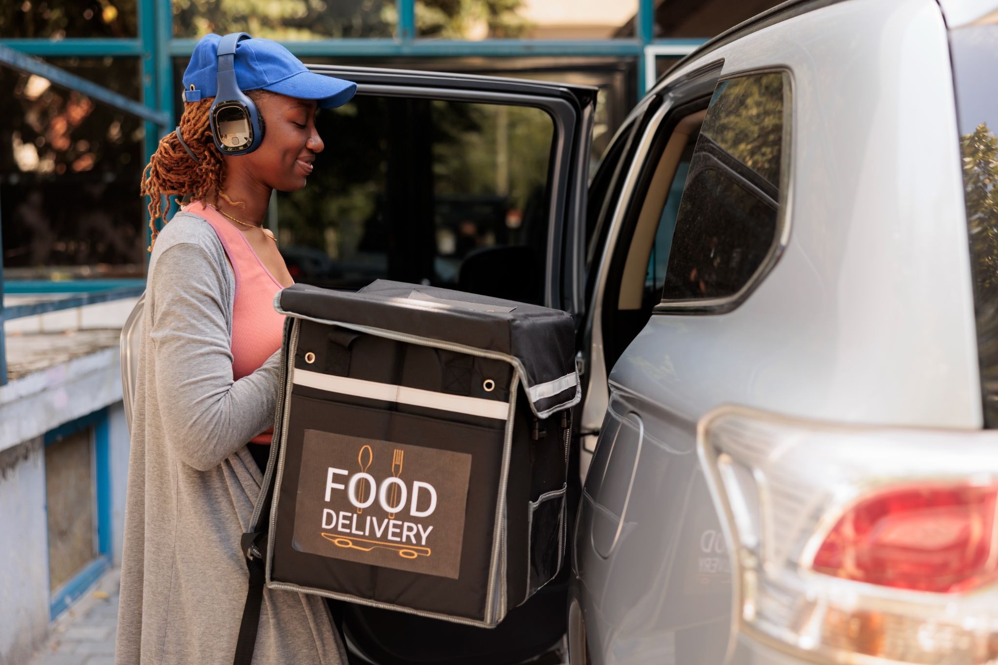 Food delivery driver loading an insulated delivery bag into a car