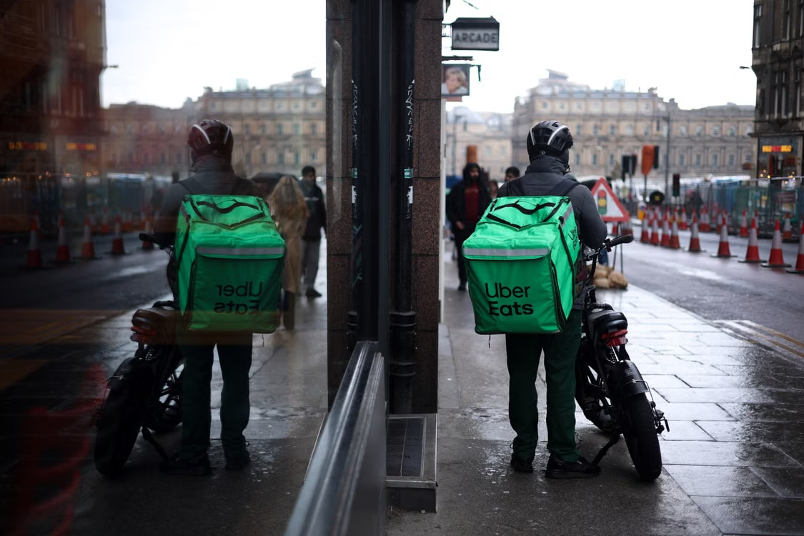 Uber Eats delivery driver checking their phone while waiting for a new pickup order