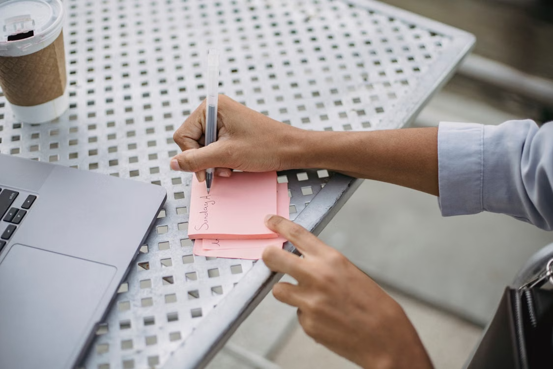 A gig worker writing notes and plans on a sticky note 
