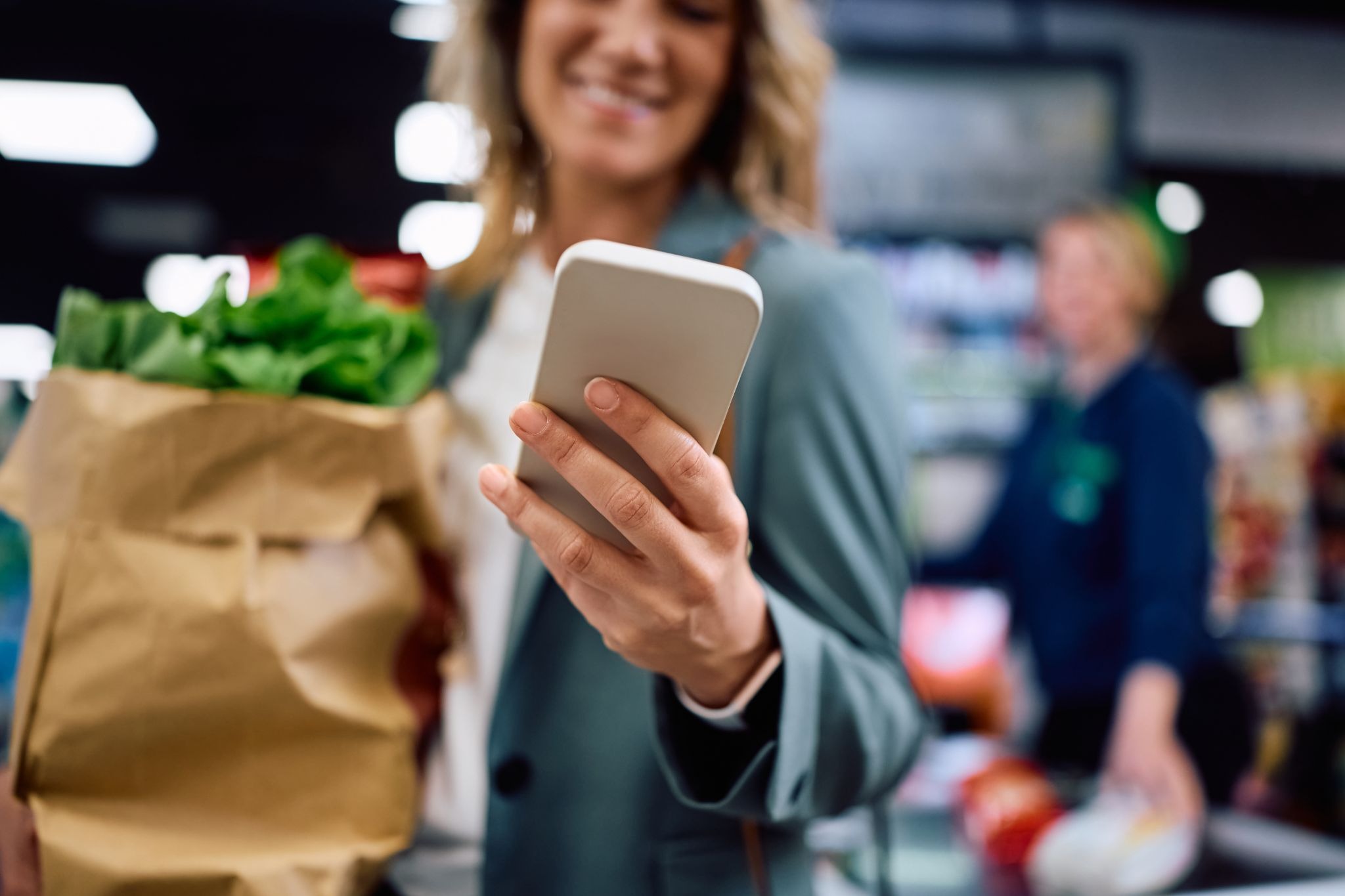 Shipt shopper checking a grocery order on a smartphone while shopping in a supermarket