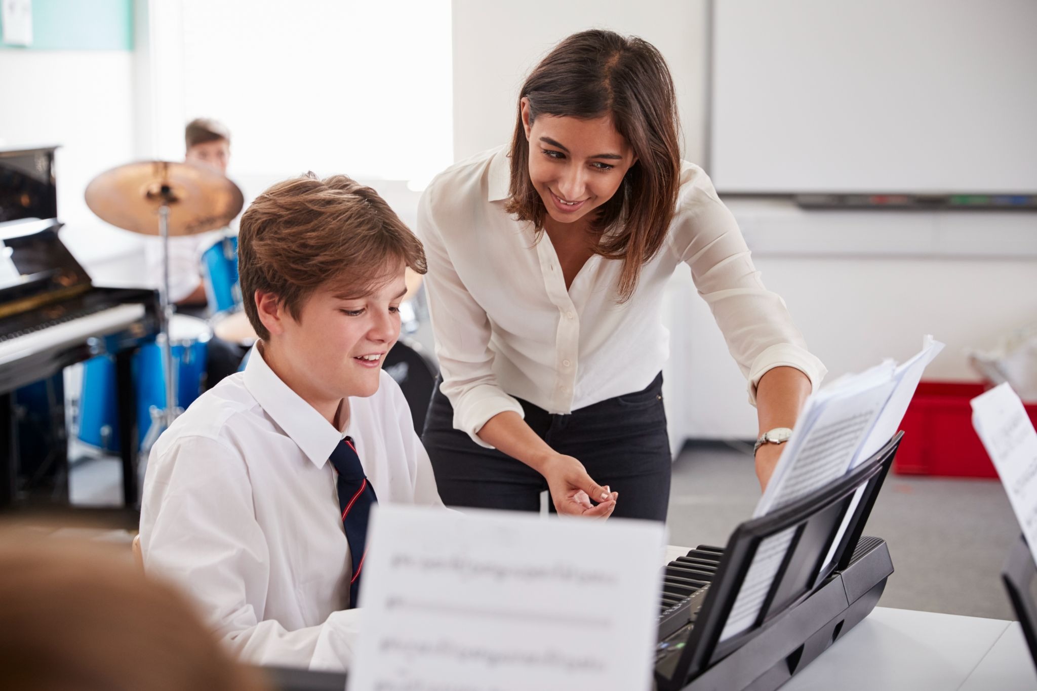 Freelance music teacher guiding a student through a piano lesson during a private class
