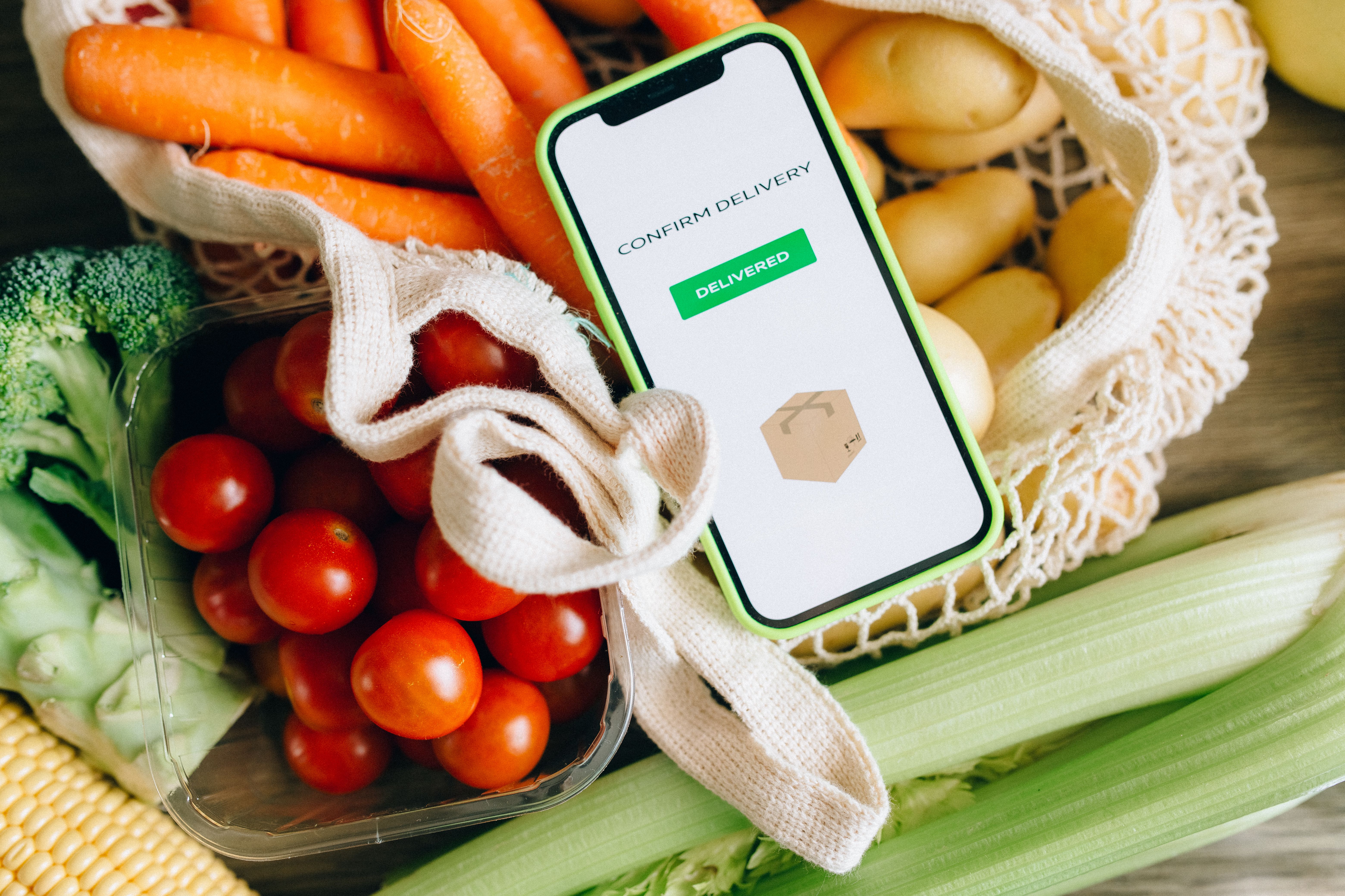 Phone displaying a delivery confirmation resting on top of a bag of groceries