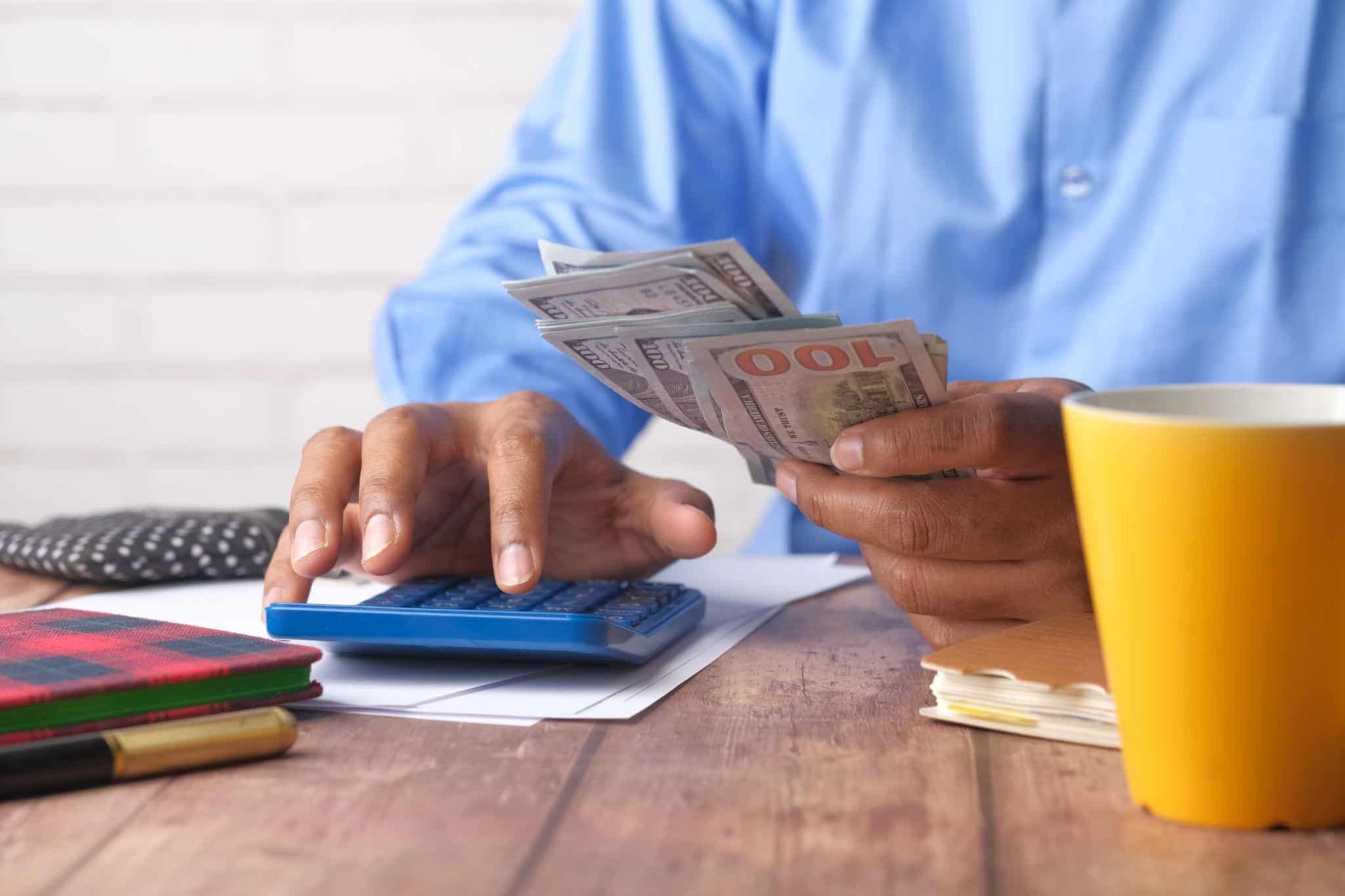 Amazon driver counting cash and using a calculator to manage personal finances.