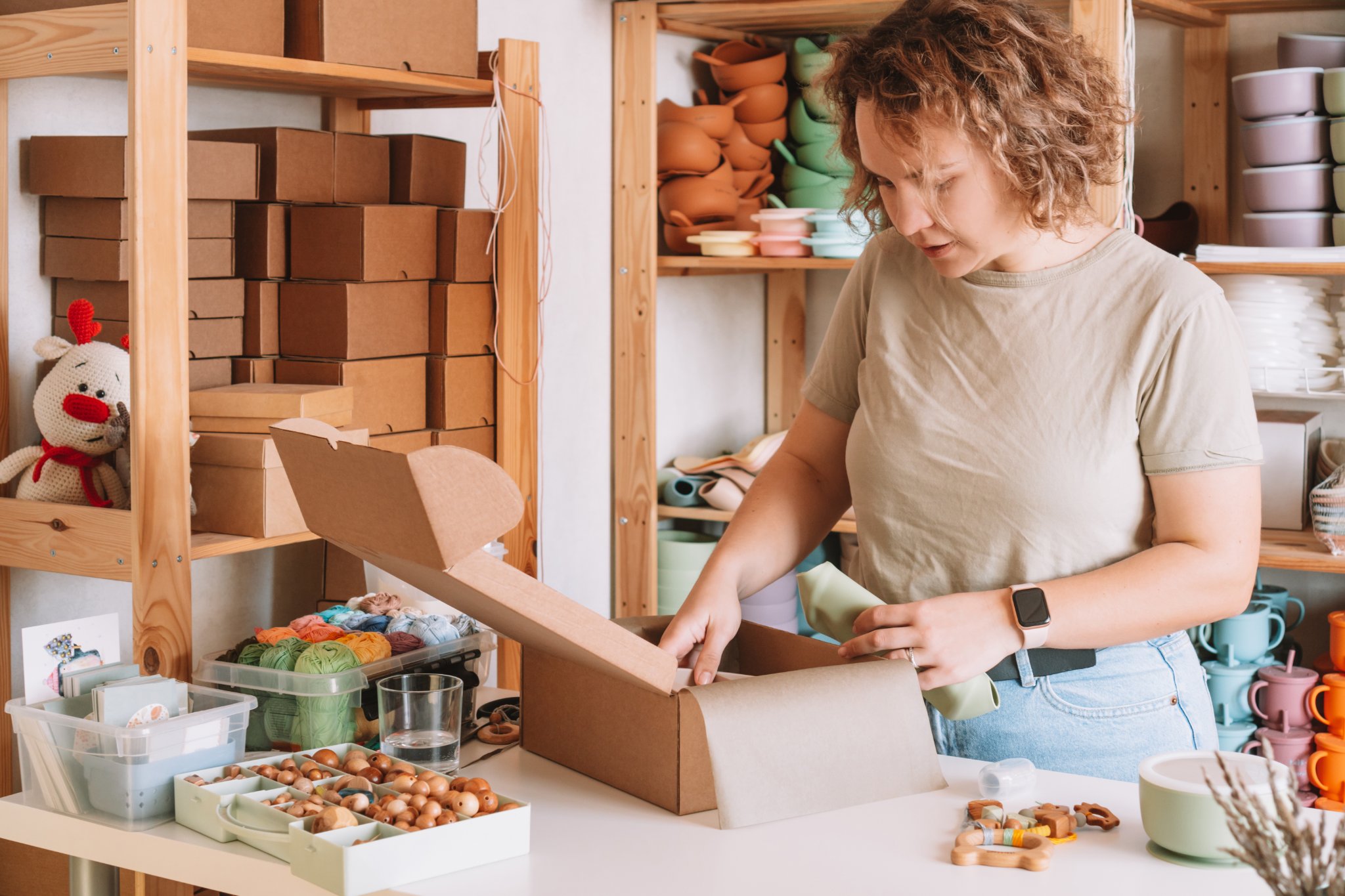 Small business owner packing orders while managing supplier costs and uncertain sales.