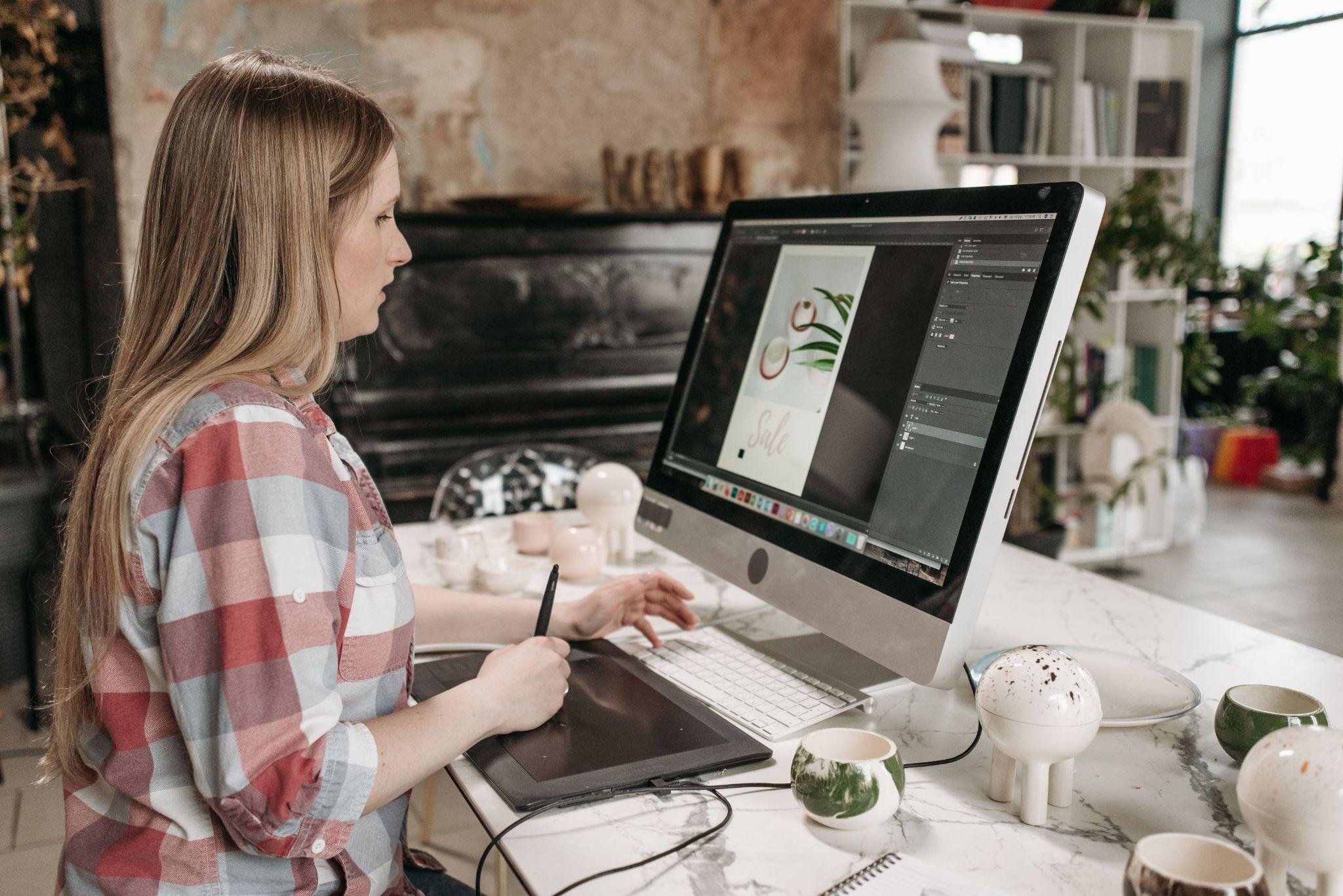 Freelance graphic designer working at a desk with a drawing tablet and 4K monitor.