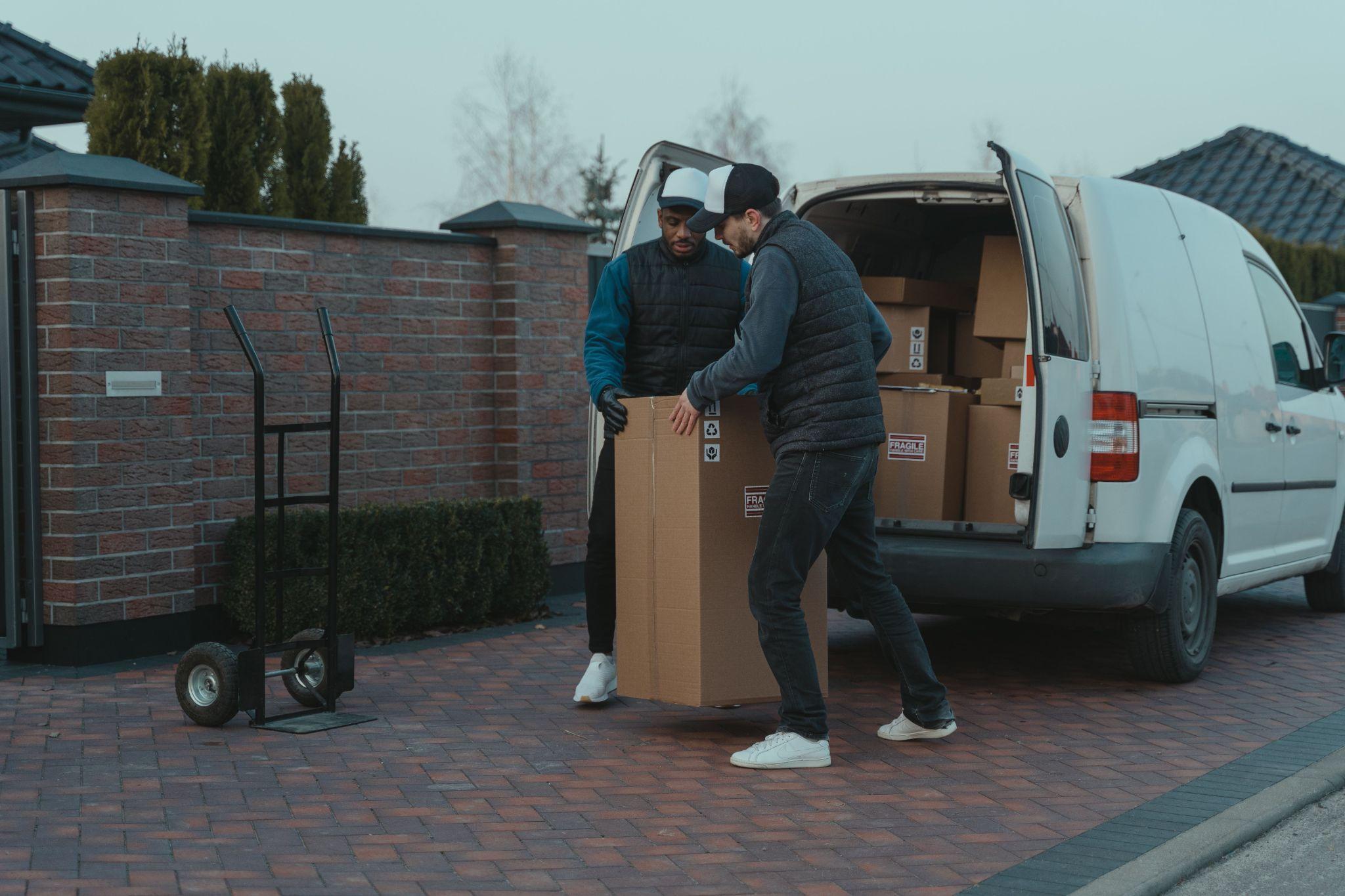 Two independent contractors about to place fragile, packed household items onto a hand trolley