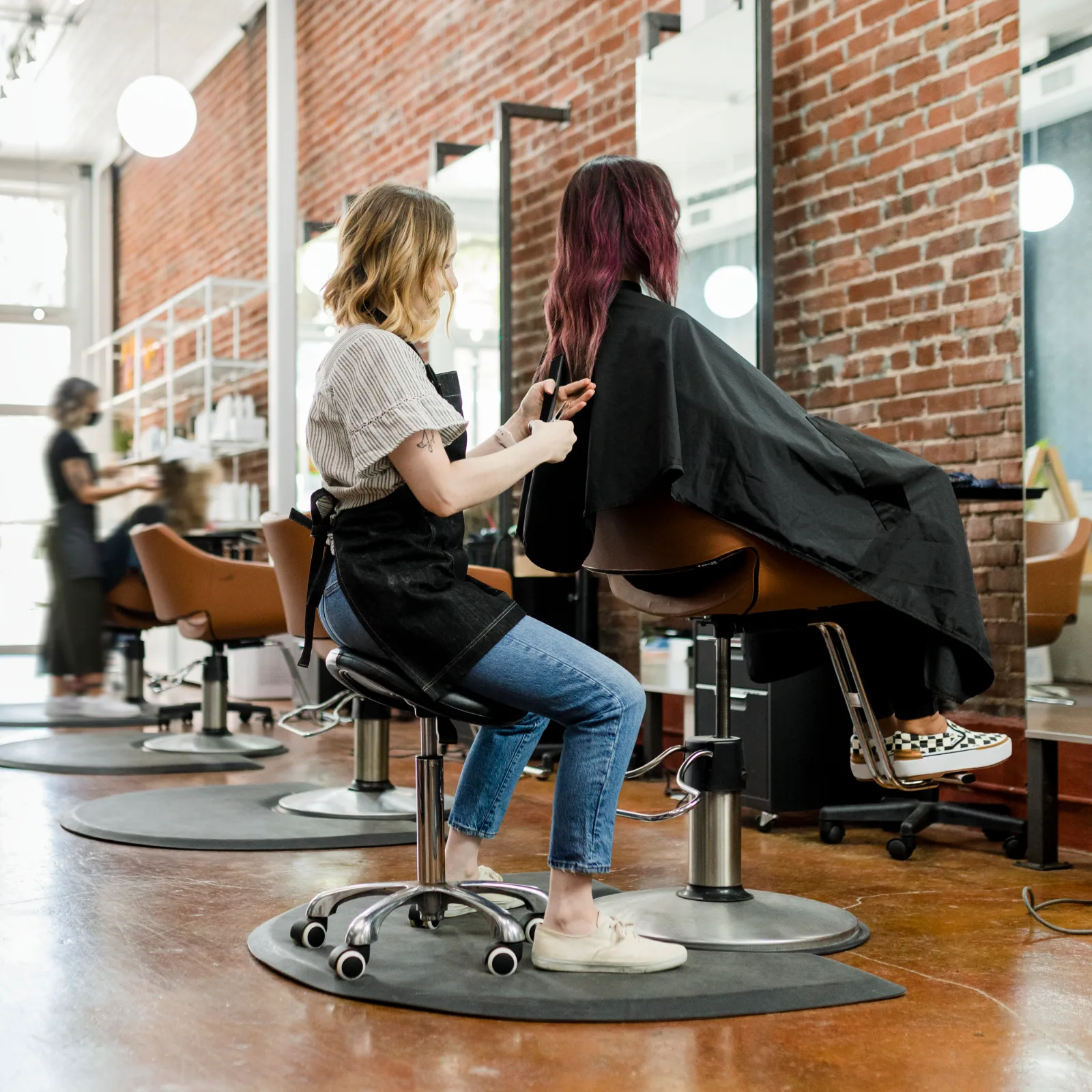 A hairstylist trims a client’s hair in a salon